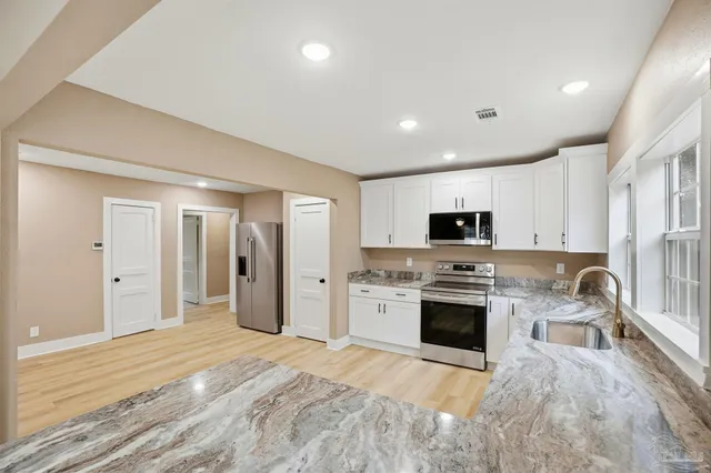 a large kitchen with stainless steel appliances granite countertop a stove and a sink