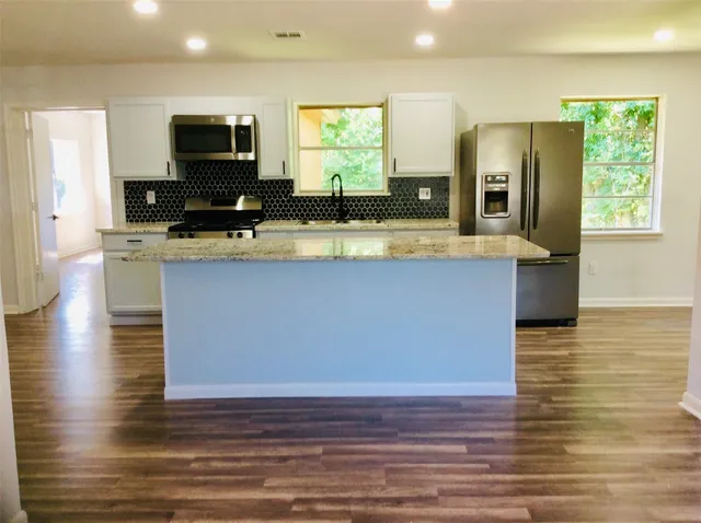 a view of kitchen with stainless steel appliances wooden floor and refrigerator