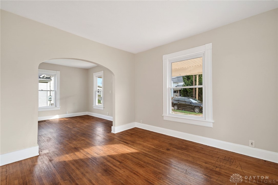 585 North Spring Street Wilmington, OH 45177 - Photo 6 of 21 This bright living area features polished wood floors and multiple windows, creating a welcoming atmosphere.