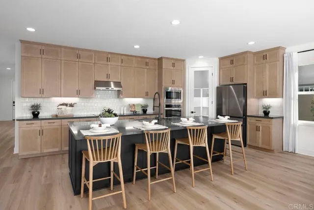 a kitchen with stainless steel appliances a dining table chairs and wooden floor