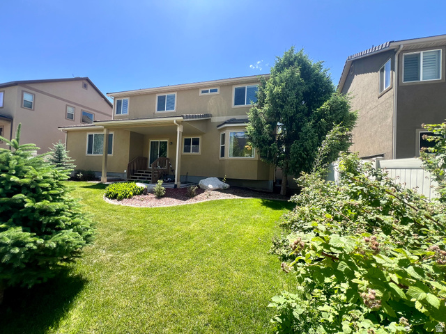 369 Culross Circle Tooele, UT 84074 - Photo 45 of 54 Spacious backyard featuring a covered patio, manicured lawn, established shrubs, mature trees, and a stucco exterior with multiple windows