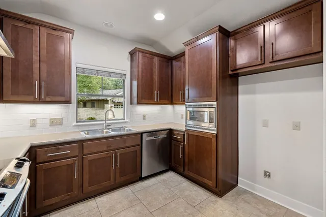 a kitchen with stainless steel appliances granite countertop wooden cabinets a sink and dishwasher a refrigerator with wooden cabinets