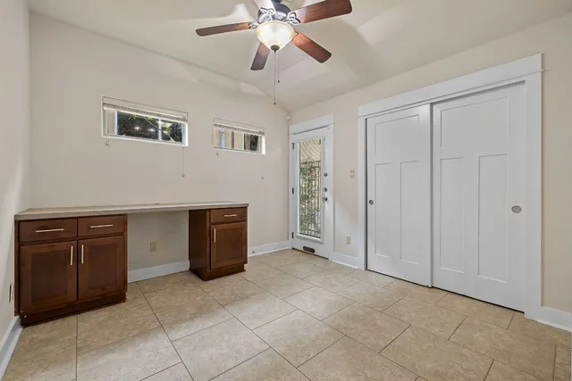 a view of an empty room with cabinet and a ceiling fan