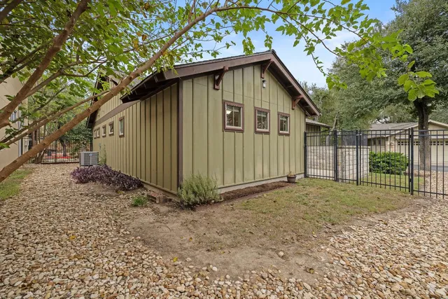a view of a house with a yard plants and large tree