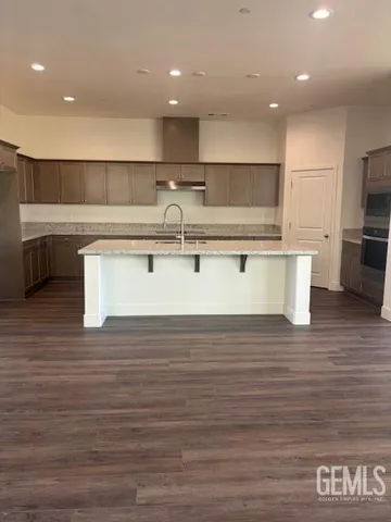 a view of kitchen with stainless steel appliances granite countertop a sink and wooden floor