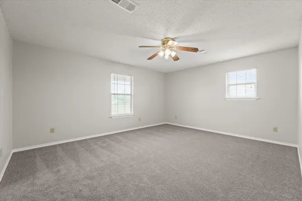 an empty room with a window and ceiling fan