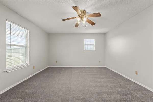 an empty room with windows and fan
