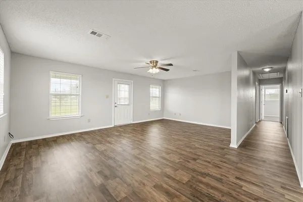 an empty room with wooden floor and windows