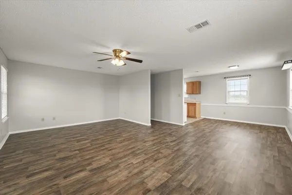 a view of an empty room with a window and wooden floor