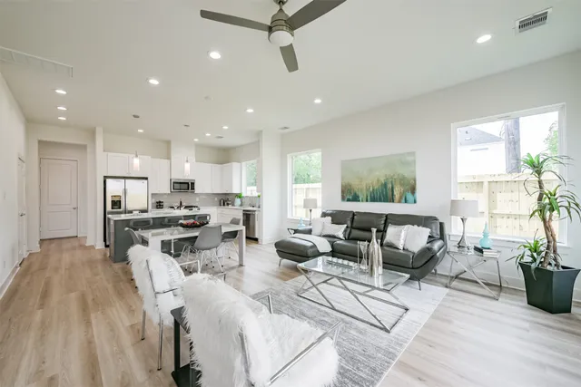a living room with furniture kitchen view and a wooden floor