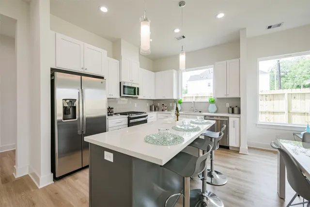 a kitchen with a refrigerator a stove a sink dishwasher with a dining table and chairs