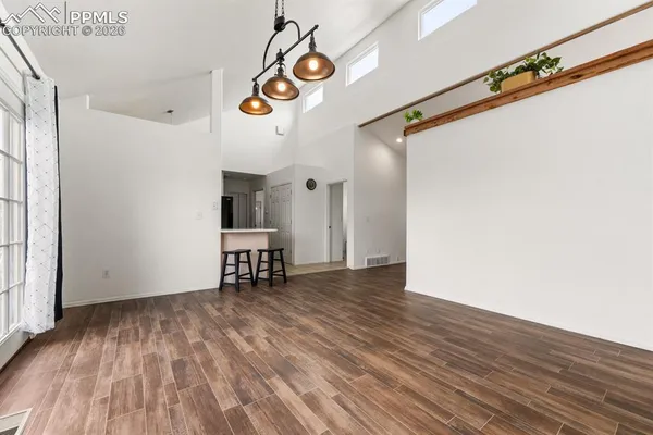 a view of an empty room with wooden floor and windows