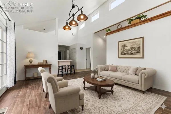 a living room with furniture kitchen view and a wooden floor