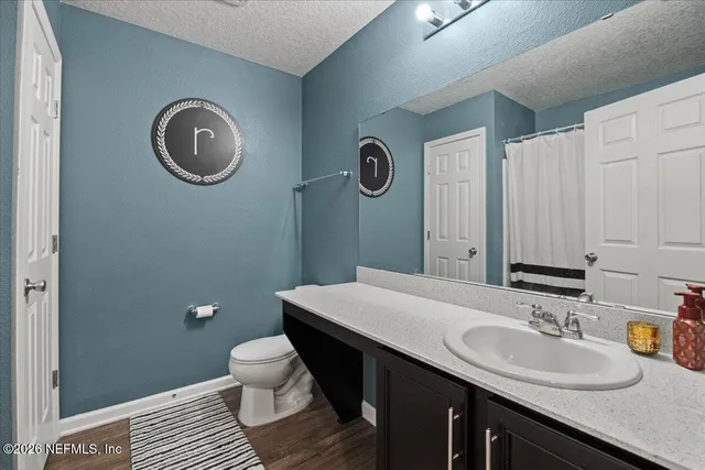 a bathroom with a granite countertop toilet a sink and a mirror