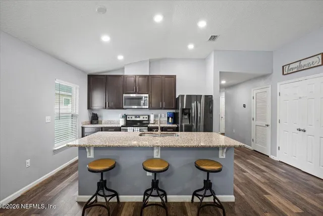 a large kitchen with granite countertop lots of counter space and stainless steel appliances