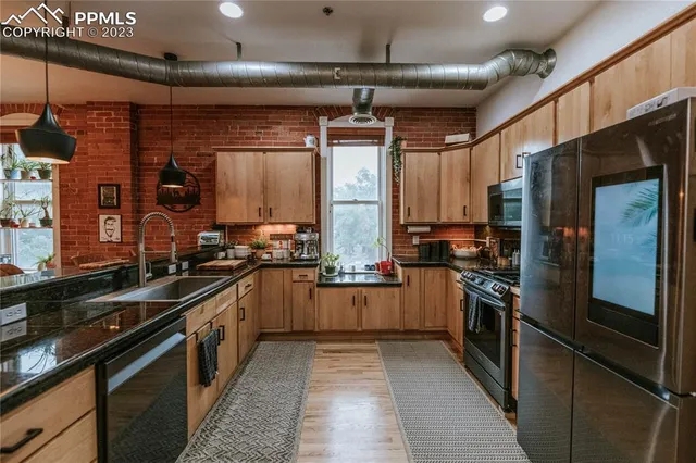 a kitchen with stainless steel appliances granite countertop a sink a stove and a refrigerator