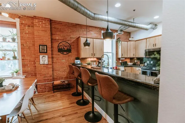 a room with stainless steel appliances kitchen island granite countertop furniture and a wooden floor
