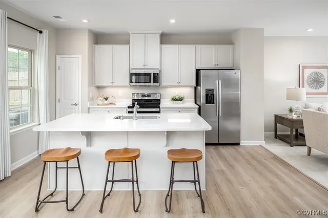 a kitchen with stainless steel appliances a dining table chairs refrigerator and microwave