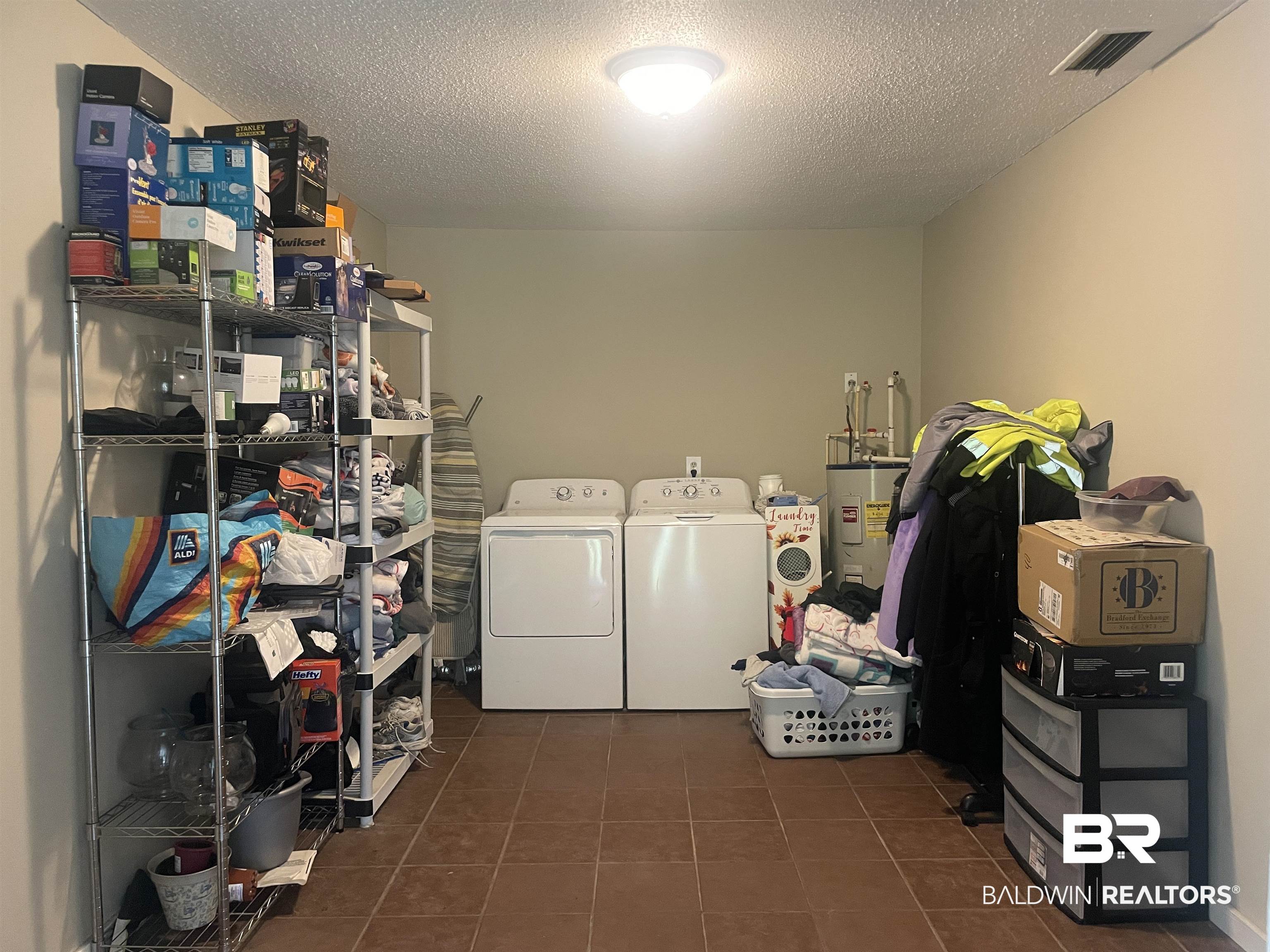 13850 Celeste Road Chunchula, AL 36521 - Photo 19 of 29 Laundry area with dark tile patterned flooring, a textured ceiling, washer and dryer, and water heater
