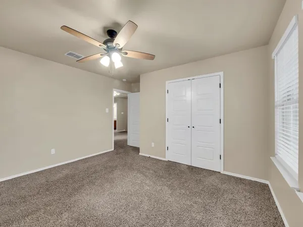a view of an empty room with a ceiling fan and window
