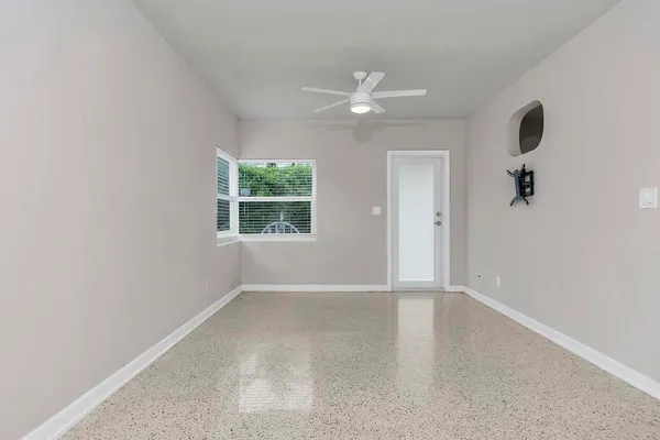 an empty room with windows and fan