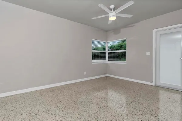 an empty room with a window and ceiling fan