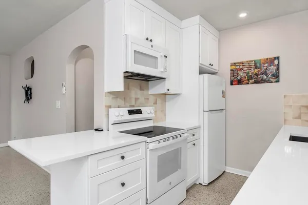 a kitchen with white cabinets and white appliances