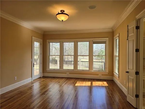 a view of an empty room with wooden floor fireplace and a window