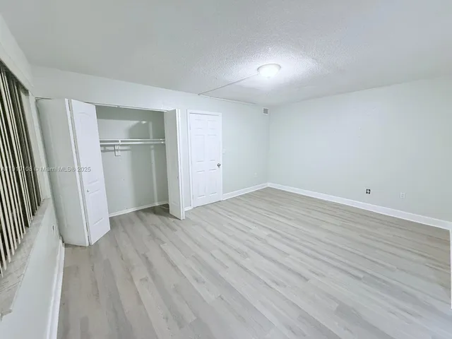 an empty room with wooden floor and entrance