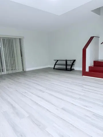 an empty room with wooden floor and lounge chair