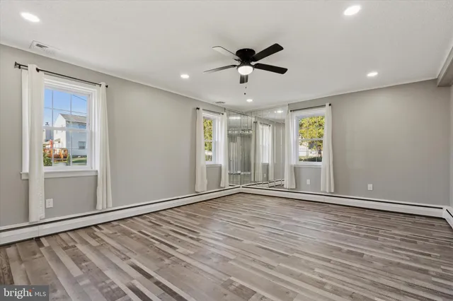 a view of empty room with wooden floor and fan