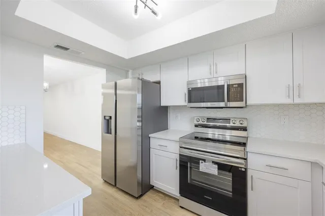 a kitchen with stainless steel appliances a stove a microwave and a hard wood floor