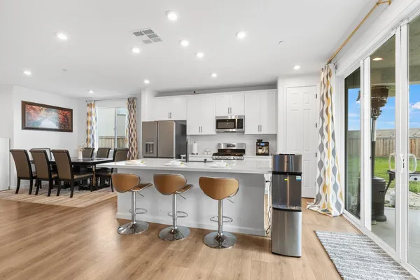 a living room with stainless steel appliances granite countertop furniture wooden floor and a view of kitchen