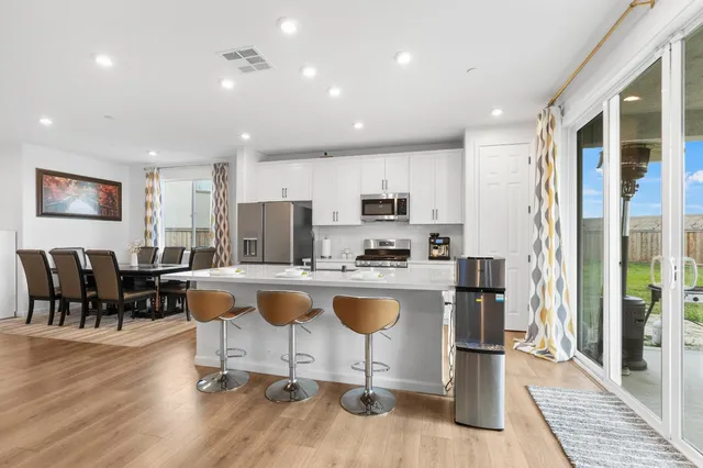 a living room with stainless steel appliances granite countertop furniture wooden floor and a view of kitchen