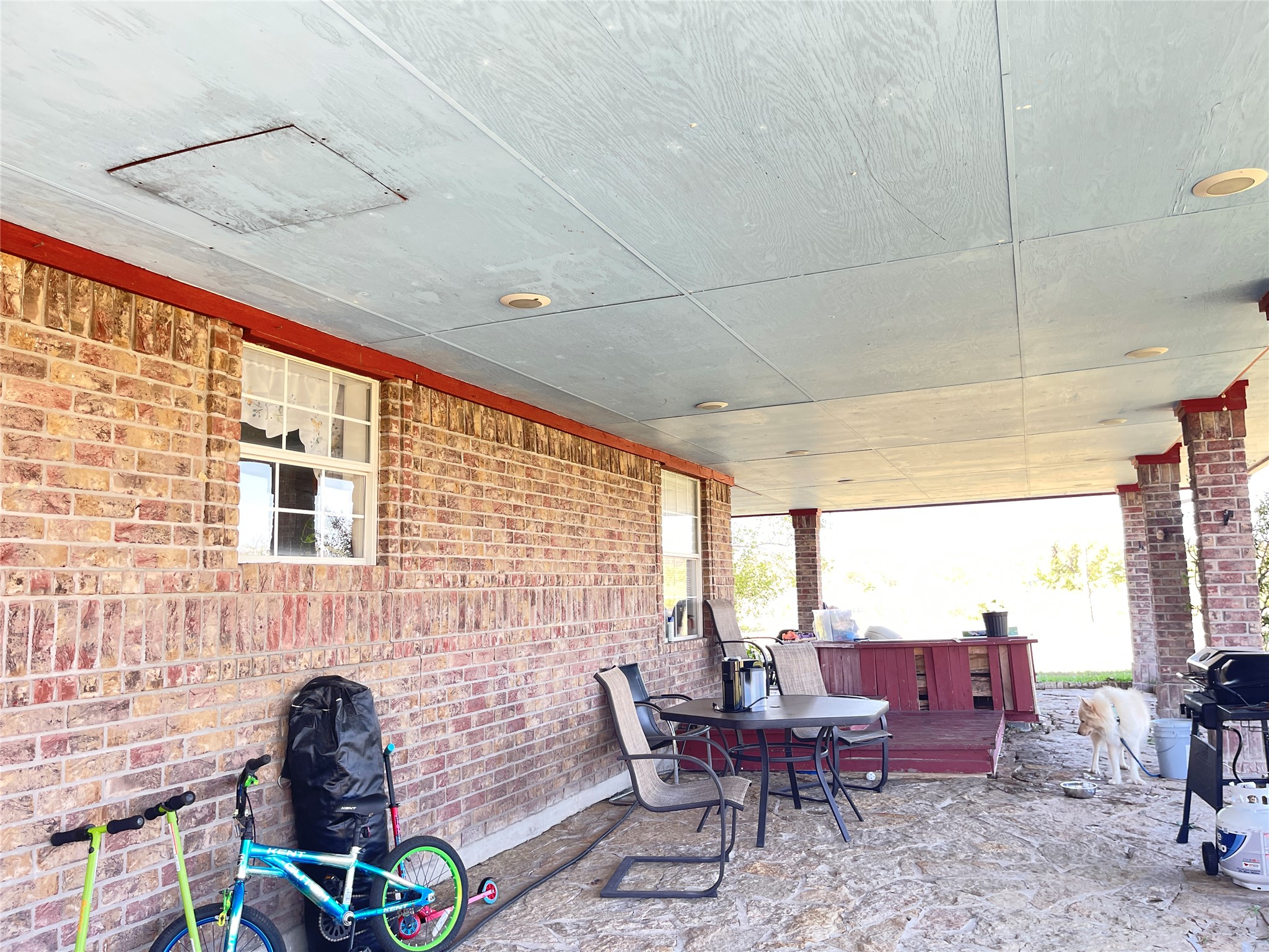 12212 Ballerstedt Road Elgin, TX 78621 - Photo 6 of 29 A spacious covered patio provides a shaded outdoor retreat alongside classic brick walls.