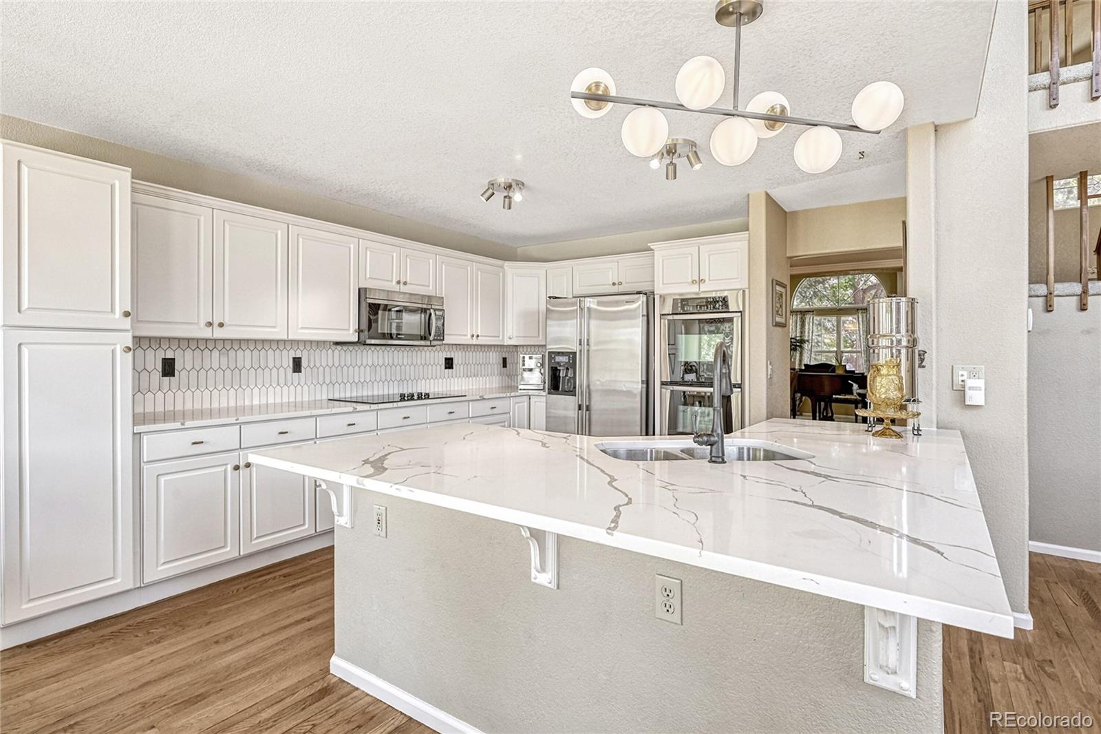 9754 Chanteclair Circle Highlands Ranch, CO 80126 - Photo 10 of 47 a kitchen with stainless steel appliances granite countertop a sink dishwasher and white cabinets with wooden floor