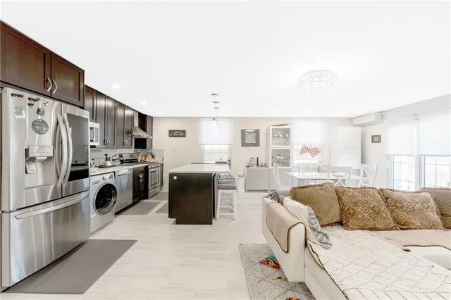 a living room with stainless steel appliances furniture and a kitchen view