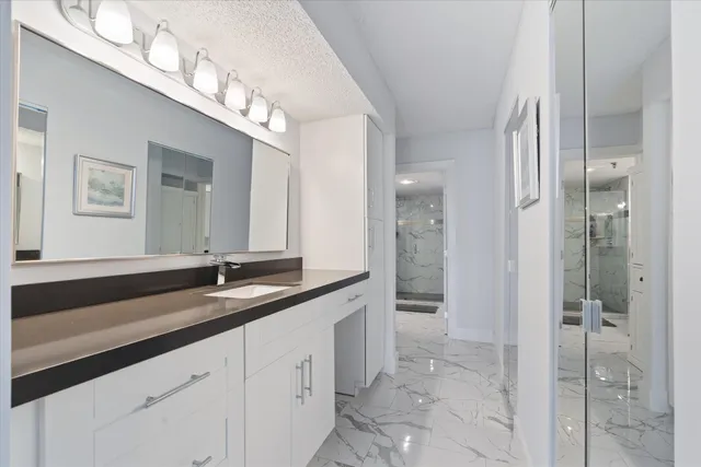 a spacious bathroom with a granite countertop sink a mirror and a shower