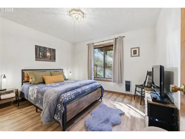 a bedroom with a bed television on desk and a window