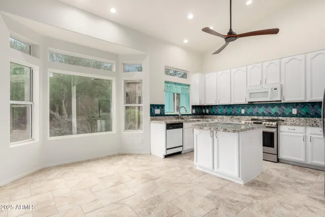 a kitchen with granite countertop white cabinets and white appliances