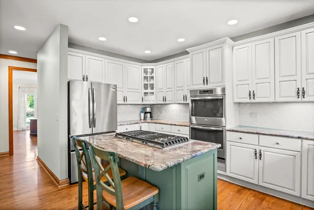 a kitchen with a refrigerator a stove and white cabinets with wooden floor