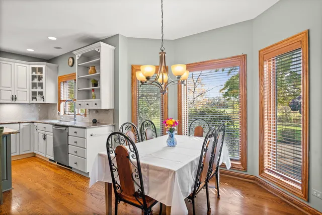 a dining room with stainless steel appliances granite countertop furniture and a large window