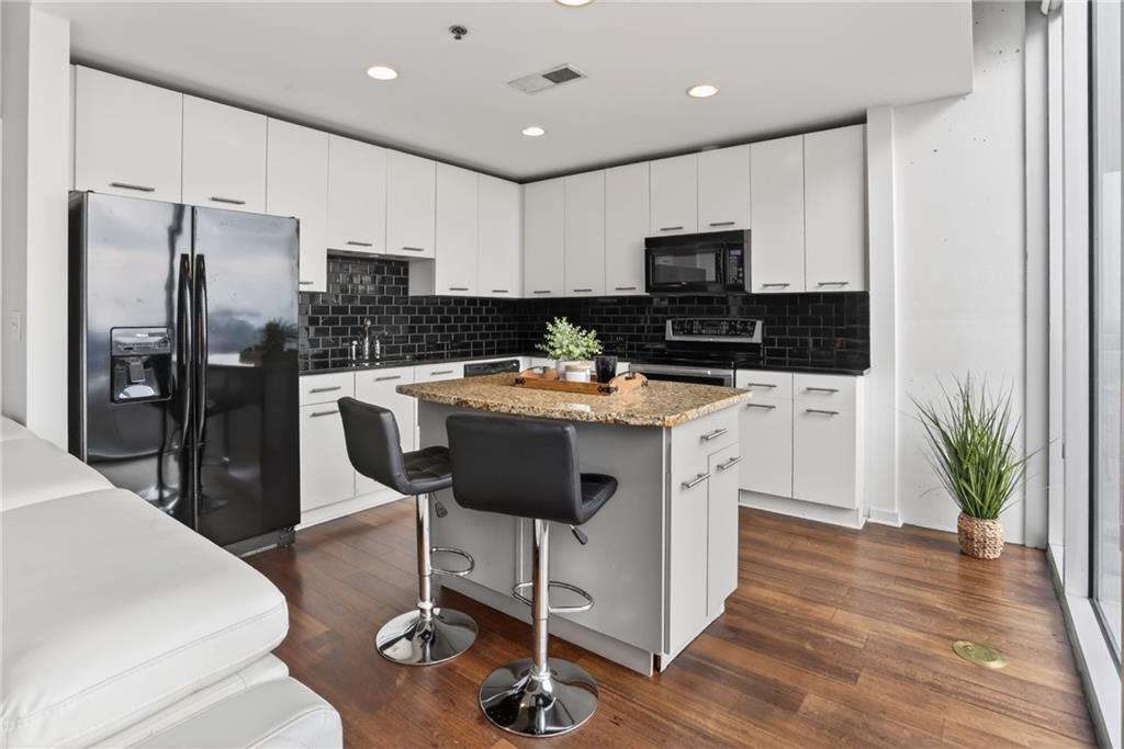 3324 Peachtree Road Northeast, Unit 1312 Atlanta, GA 30326 - Photo 16 of 23 a kitchen with stainless steel appliances granite countertop a stove top oven a refrigerator a sink and a dining table with wooden floor