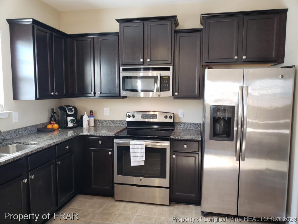 211 Rainmaker Street Linden, NC 28356 - Photo 8 of 34 a kitchen with granite countertop stainless steel appliances and wooden cabinets