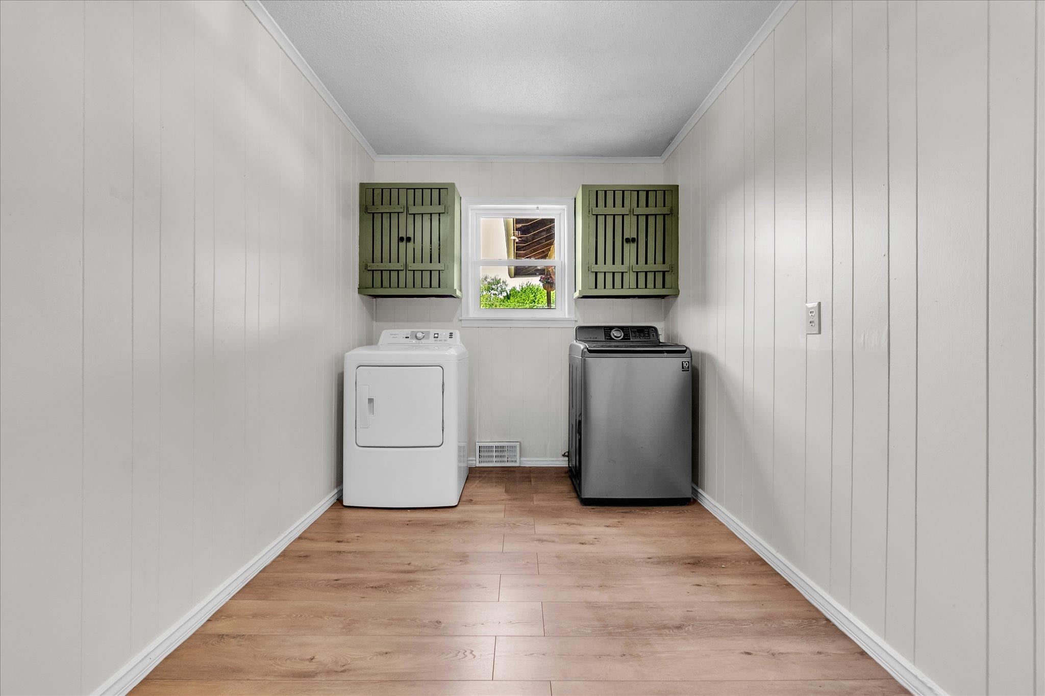 885 Rebel Road Piperton, TN 38017 - Photo 18 of 30 Laundry area with washing machine and clothes dryer, light wood finished floors, crown molding, and wood walls