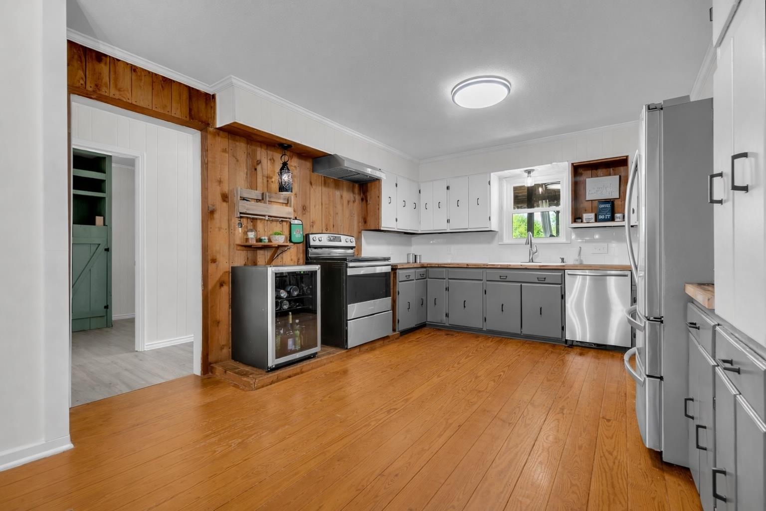 885 Rebel Road Piperton, TN 38017 - Photo 21 of 30 Kitchen featuring two tone cabinetry, ornamental molding, stainless steel appliances, wooden walls, and light wood-type flooring