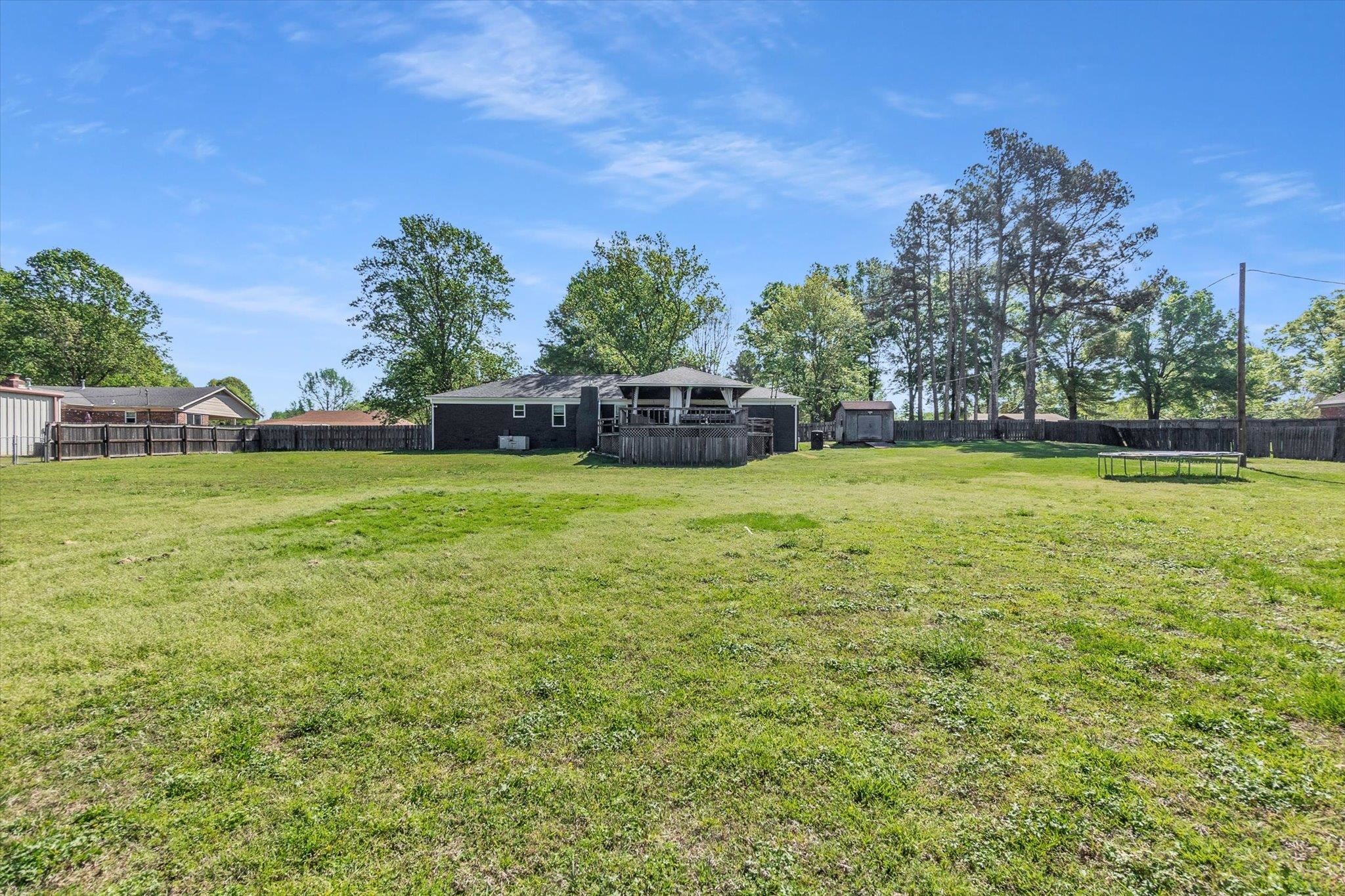 885 Rebel Road Piperton, TN 38017 - Photo 28 of 30 Fenced backyard with a trampoline, a wooden deck, and an outdoor structure