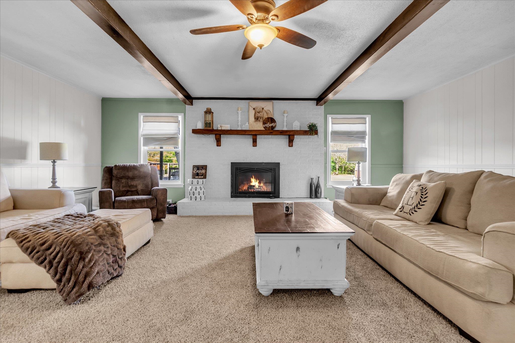 885 Rebel Road Piperton, TN 38017 - Photo 7 of 30 Carpeted living area featuring beam ceiling, a fireplace, wood walls, a ceiling fan, and a decorative wall