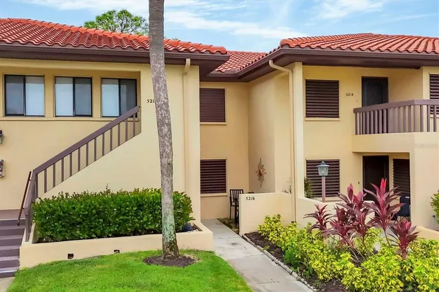 a view of a house with small yard plants and large tree