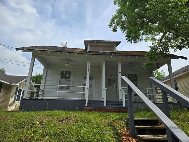 a view of a house with a small yard and a large tree